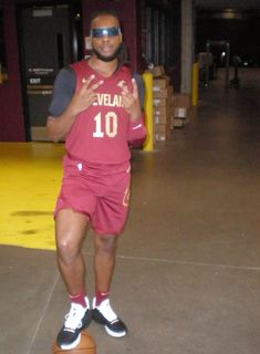 a man standing on top of a basketball ball wearing a red uniform and goggles