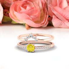 two different rings with yellow and white diamonds on each ring, next to pink roses