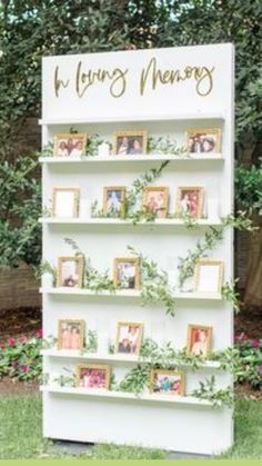 a wedding memory board with photos and greenery on it in front of some trees