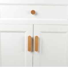 a white cabinet with wooden handles and knobs