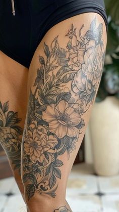 a woman's legs with tattoos on them and flowers in the bottom part of her leg