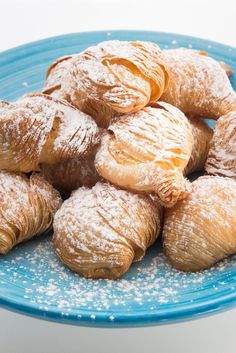 a blue plate filled with powdered sugar covered pastries on top of a table