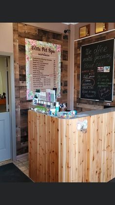 a wooden counter with lots of bottles on it in front of a chalk board wall