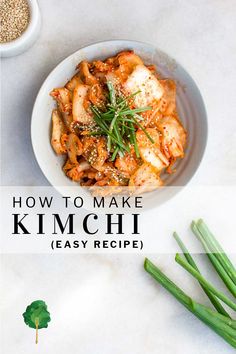 a white bowl filled with kimchi and green onions on top of a marble counter