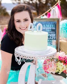 a woman sitting in front of a cake with the number 20 on it and flowers