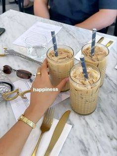 two people sitting at a table with drinks in front of them and the words happiness written on their cups