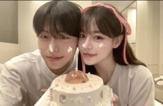 two people pose with a cake in front of their face and one is holding a candle