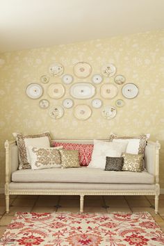 a white couch sitting in front of a wall with plates on it