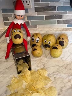 an elf is sitting on top of potatoes with eyes drawn on them and some potato chips