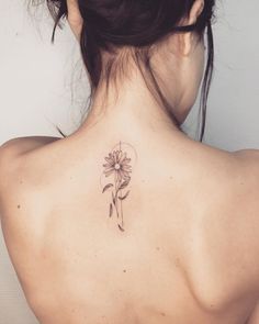 a woman with a flower tattoo on her back shoulder and behind her is a sunflower