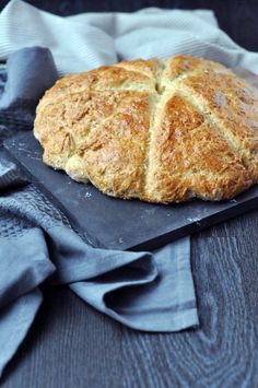 a loaf of bread sitting on top of a cutting board next to a blue napkin