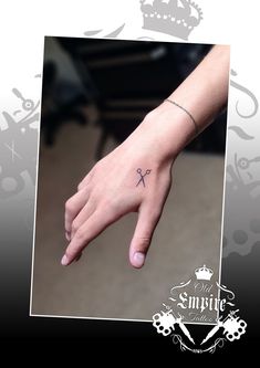 a hand with a small cross tattoo on it