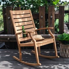 a wooden rocking chair sitting on top of a deck next to a potted plant