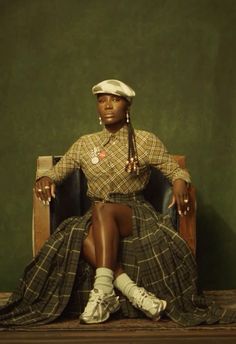 a woman sitting on top of a wooden chair wearing a hat and dress with long hair