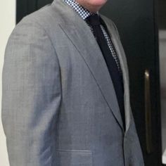 a man wearing a suit and tie standing in front of a door