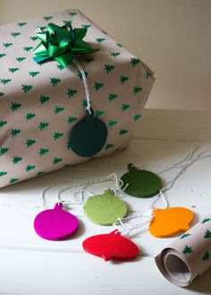 a present wrapped in green and white paper next to some christmas decorations on a table