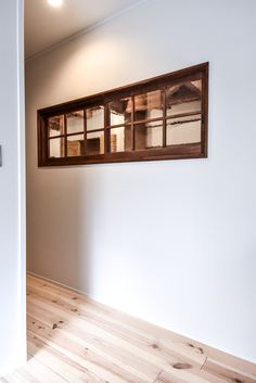 an empty room with wood flooring and a window on the wall above it that has glass panes