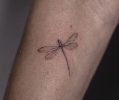 a small dragonfly tattoo on the arm