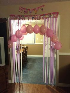 a birthday party with balloons and streamers on the door way to a room filled with furniture