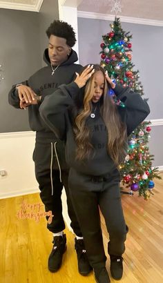 two people standing in front of a christmas tree