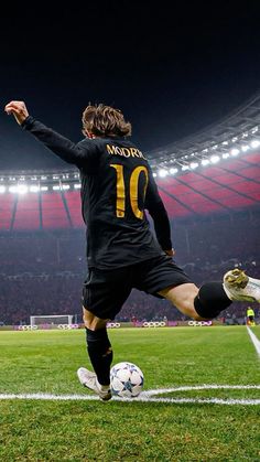 a man kicking a soccer ball on top of a field in front of an empty stadium