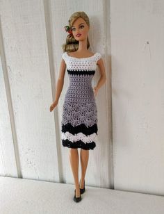 a crocheted doll is standing next to a white wall