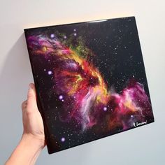 a person holding up a painting with space in the background