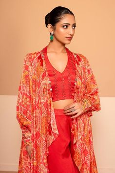 Red bishop sleeves cape with all over fleur art print and sequin highlights. Paired with a halter neck sequin embroidered blouse and a gharara pant. - Aza Fashions Red Bohemian Tops For Navratri, Designer Red Long Sleeve Blouse, Red Long Sleeve Palazzo Set For Festivals, Designer Long Sleeve Red Blouse, Red Long Sleeve Designer Blouse, Red Long Sleeve Palazzo Set For Designer Wear, Bollywood Style Red Long Sleeve Tops, Red Designer Wear Set With Cape Sleeves, Red Designer Sets With Cape Sleeves