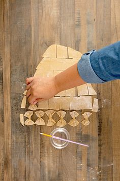 a person is cutting out wooden shapes on a wood floor with scissors and glues