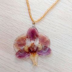 ☀️ Embrace the timeless beauty of orchids with this captivating handmade necklace! This exquisite necklace is more than just an accessory; it's a wearable work of art that captures the elegance and sophistication of orchids. Unlike traditional dried flowers, the orchid in this necklace is preserved in crystal-clear resin, ensuring its long-lasting beauty! Here's what makes this necklace truly special: Uniquely handcrafted: I cultivate and preserve the orchids myself, ensuring each necklace is a one-of-a-kind creation. You won't find another piece exactly like it! Even the flowers from the same orchid vary slightly in size and colour.  Timeless orchid design: The orchid's graceful silhouette and vibrant colors add a touch of sophistication and elegance to any outfit. Durable resin pendant: Unique Orchid-colored Jewelry As A Gift, Unique Orchid Jewelry For Gift, Unique Orchid-colored Jewelry Gift, Unique Orchid Colored Jewelry For Gift, Orchid Flower Pendant Jewelry Gift, Orchid Flower Pendant Jewelry For Gift, Orchid Flower Necklace For Gift, Unique Flower-shaped Birth Flower Necklaces, Unique Birth Flower Necklace