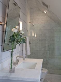 a bathroom with a sink, shower and flowers in the vase on the counter top