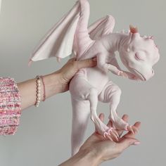 a person holding a pink dragon toy in their left hand, with another one being held up to the camera