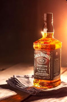 a bottle of jack daniels whiskey sitting on top of a wooden table next to a cloth