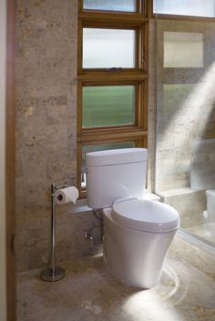 a white toilet sitting next to a window in a bathroom