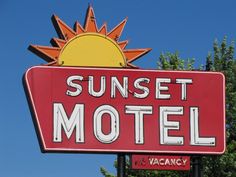 a red motel sign with the sun on top