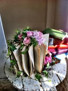 an open book sitting on top of a wooden table next to flowers and bookshelves