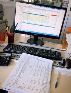 a computer monitor sitting on top of a desk next to a keyboard and calculator