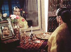 a woman sitting in front of a mirror next to a table