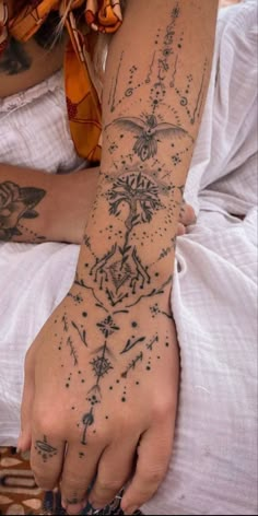 a woman's arm with tattoos on it and her hand in the air,