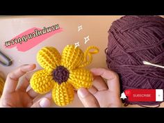 someone crocheting a flower with yarn next to a ball of yarn and scissors