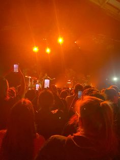 a large group of people at a concert with their cell phones up in the air