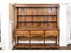 an old wooden desk with two drawers and a shelf on one side, in front of a white wall