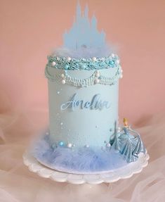 a blue and white birthday cake with a princess castle on top, surrounded by fluffy tulle