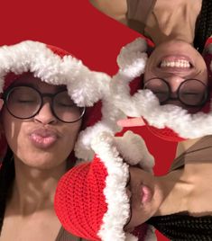 two women wearing santa hats and glasses making funny faces