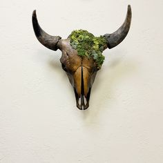 an animal's head with plants on it is mounted to the side of a wall