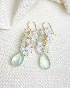 These are a luxe little adornment for your ears! Enjoy the indulgent shimmer of petite prehnite, moonstone, and crystal quartz clusters all crowning ethereal faceted prehnite briolettes. Each hand-picked gem is accented and hand-wrapped in 14k gold-fill. The gold-filled ear wires are smooth and comfortable for effortless wear. What I love the most about these earrings is the soft green and white colors. These can be worn festively for the holidays, but also will carry you through your spring and Elegant Prehnite Gemstone Jewelry, Moonstone Crystal, Moonstone Beads, Quartz Beads, Summer Styles, Quartz Cluster, White Colors, Earrings Drop, Cluster Earrings