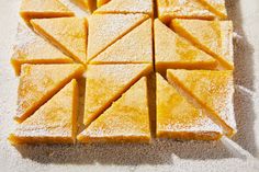 several pieces of yellow cake sitting on top of a white tablecloth covered in powdered sugar