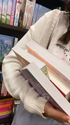 a girl is holding several books in her hands