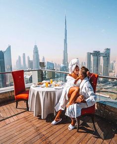 a man and woman sitting at a table on top of a building in the city