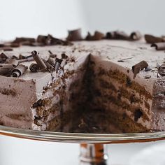 a chocolate cake with frosting and sprinkles on a glass platter